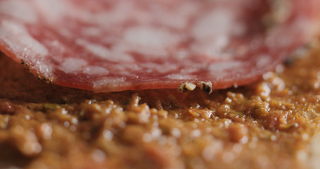 Extreme closeup laying salami slices on ciabatta
