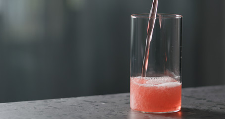 pour berry cider into glass on terrazzo countertop with copy space © GCapture
