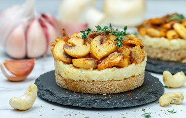 Delicatessen snack for vegetarians (vegans) of fried mushrooms with onions, garlic, thyme and cashew nuts on bread slices. Selective focus