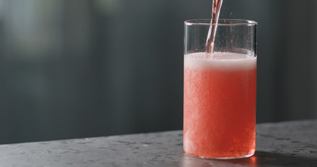 pour berry cider into glass on terrazzo countertop with copy space © GCapture