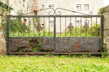 Old rusty elegant metal gate door lead to green garden
