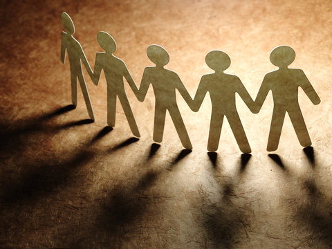 Group of paper people holding hands.