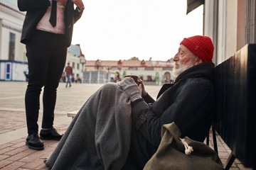 businessman came up and help homeless man sitting on the floor. Help, money donation to vagrant male in the street