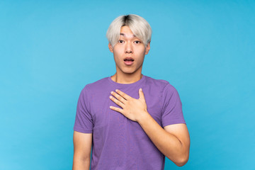 Young asian man over isolated blue background surprised and shocked while looking right