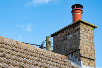 Large, english cottage style brick chimney showing a newly installed terracotta pot together with a...
