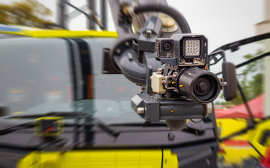 Fototapeta na wymiar Modern firefighting system mounted on a hydraulic arm of a fire truck - high pressure nozzle with a camera and lighting; blurred background