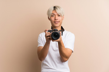 Young asian man over isolated background with a professional camera