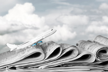 Plane, old Newspapers on the background of the cloudy sky. Concept of world news information.