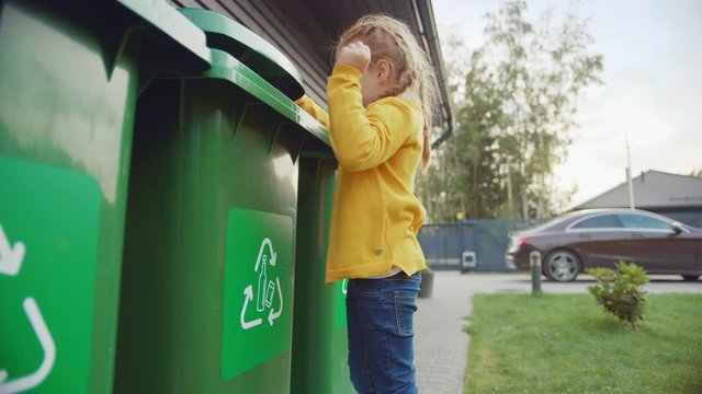 Young Girl is Walking Outside Her House in Order to Throw Away an Empty Plastic Bottle into a Trash Bin. She Uses Correct Garbage Bin Because This Family is Sorting Waste and Helping the Environment.