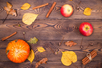 Top view of mini-pumpkins and fallen autumn leaves, apples, cinnamon sticks on a wooden background. Happy Thanksgiving and Harvest Day