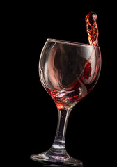 a splash of red wine in a glass on a black background