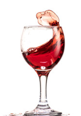 a splash of red wine in a glass on a white background