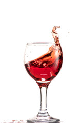 a splash of red wine in a glass on a white background