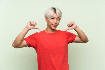 Fototapeta premium Young asian man over isolated green background proud and self-satisfied