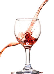a splash of red wine in a glass on a white background
