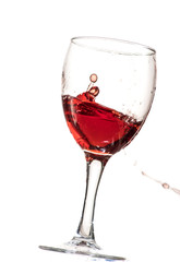 a splash of red wine in a glass on a white background
