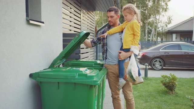 Father Holding a Young Girl and Going to Throw Away an Empty Bottle and Food Waste into the Trash. They Use Correct Garbage Bins Because This Family is Sorting Waste and Helping the Environment.