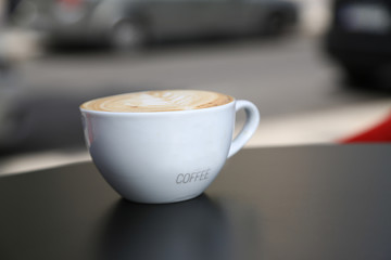Cup of cappuccino with latte art.  Hot coffee on table. White cup of cappuccino stands on the table, selective focus