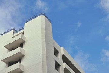 Corner of white concrete office building with soft blue sky, Angle view from below.