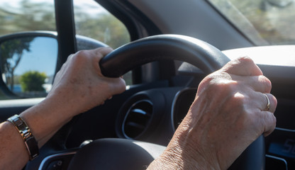 Hands of a woman on a steering wheel