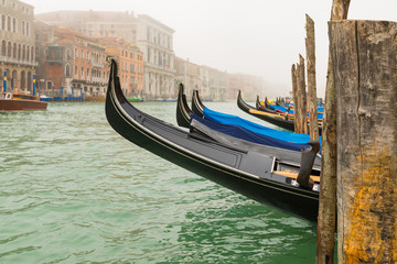 Fototapeta na wymiar Gondolas moored by Saint Mark square in a foggy morning
