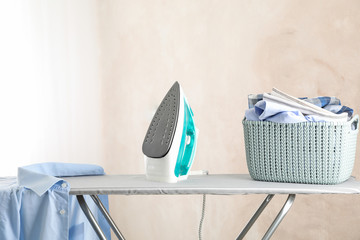 Iron and basket with clear laundry against light background, space for text