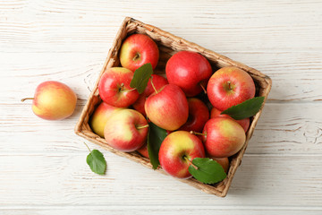 Basket with apples on white wooden background, top view