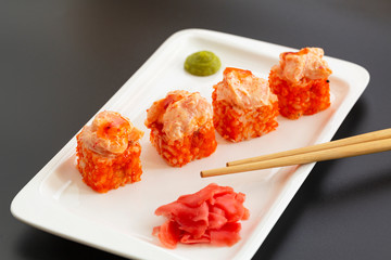 Japanese seafood sushi. Sushi rolls, wasabi, pickled ginger and chopsticks on a white plate. Selective focus