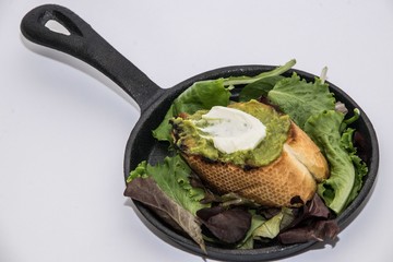 Close up of a guacamole tapa with green leaves on a iron skillet
