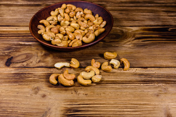 Ceramic plate with roasted cashew nuts on a wooden table