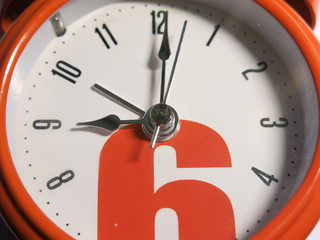 orange alarm clock with arrows