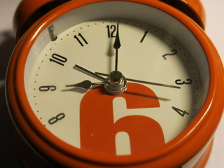 orange alarm clock with arrows