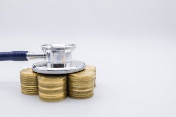 Money, Finance and Health Care concept. Close up of  stethoscope on top of row of stack of gold coins on white background and copy space.