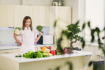 Kitchen and vegetables. Girl holds broccoli in hand.