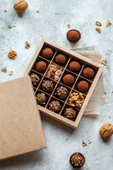 Set of chocolate truffles with nuts and cocoa. Tasty round candy. A delicious gift in a Kraft paper box. Holiday concept. Selective focus