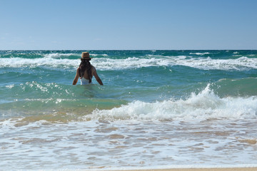 Fototapeta premium summer a young woman walks into the swirling sea