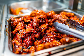 Barbeque sauce chicken wings buffet bar self serve with tongs in grocery store, restaurant or...