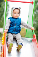 Two-year-old brightly dressed boy is playing on the playground