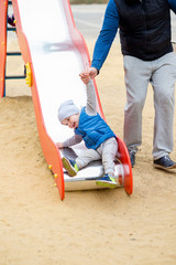 Two-year-old brightly dressed boy is playing on the playground