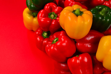 Fresh red, yelow, green bell pepper on a red background.