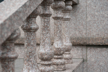 A stone staircase made of granite. A fragment of the railing with shaped columns. Selective focus.