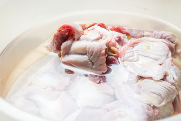 Thawed and washed chicken gizzards in eggplant on the kitchen table for cooking soup.
