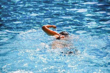 Detailansicht RÃ¼cken: Junge Schwimmerin trainiert konzentriert im Schwimmbecken im Freibad...
