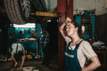 The concept of small business, feminism and women's equality. A young female auto mechanic wearily...