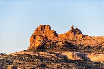 Balanced rock on cliff in Arches National Park butte view in Utah during morning sunrise with orange color