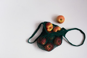 Zero waste concept. Red and yellow apples in green textile bag.