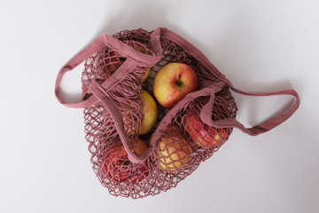 Zero waste concept. Red and yellow apples in pink textile bag. Flat lay