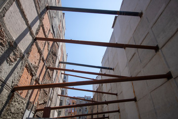 Iron supports placed between two buildings. In the background old buildings and construction in the middle. Iron pipes were laid to prevent two buildings from collapsing.