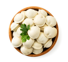 Dumplings with parsley leaves in a wooden plate on a white background. The view of top.
