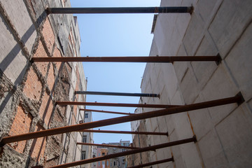 Iron supports placed between two buildings. In the background old buildings and construction in the middle. Iron pipes were laid to prevent two buildings from collapsing.